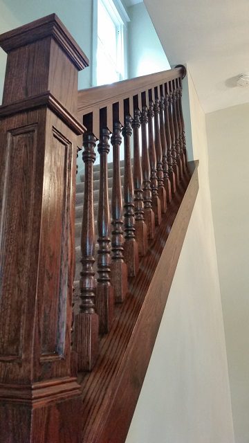 A wooden staircase with a railing and handrail.