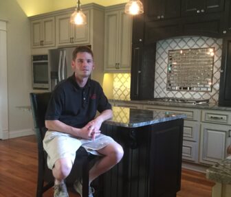 A man sitting in front of a kitchen island.